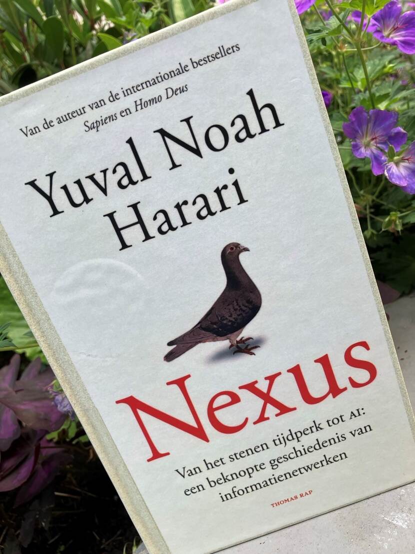Foto van kaft van boek Nexus van Yuval Noah Harari in tuin voor bloemen