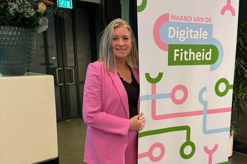 Wilma de Groot poseert bij banner van de Maand van de Digitale Fitheid