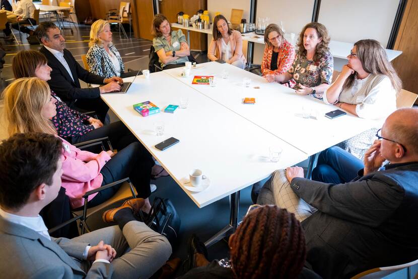 Groep aanwezigen in gesprek rondom tafel met elkaar over proactieve dienstverlening